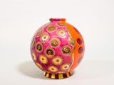 un vase rose et orange posé sur une surface blanche