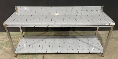 une table en acier inoxydable surmontée de deux étagères