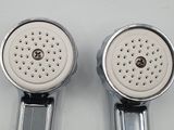 two chrome shower heads on a white surface
