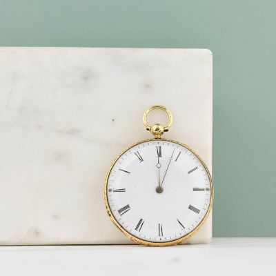 un bloc de marbre blanc sur lequel repose une montre de poche en or