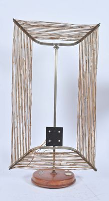 un petit objet métallique reposant sur un socle en bois, sur fond blanc