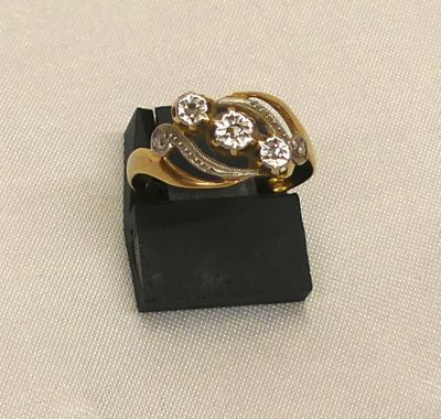 bague en or et diamants posée sur un socle noir, sur un tissu blanc