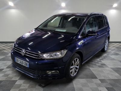 La Volkswagen Touran bleue est garée sur un sol en carrelage à damier.