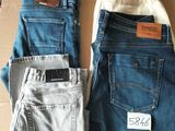 two pairs of men ' s jeans sitting on top of a cardboard box