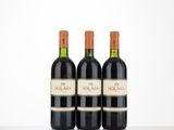 three bottles of red wine sit on a table