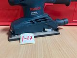 une ponceuse orbitale Bosch posée sur une table, avec son étiquette de prix