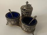 two silver and blue glass containers with spoons on a white surface