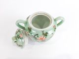 une petite tasse avec un couvercle posée sur une surface blanche