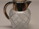 a small glass pitcher with a silver lid on a table