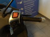 a close up of a motorcycle handlebar with a blue sign in the background
