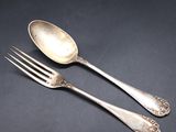 two silver spoons and a fork on a black surface