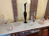 a black vase sitting on top of a table next to other glass vases