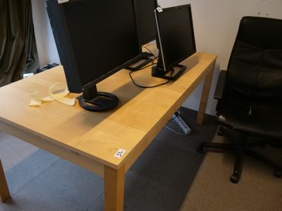 un bureau sur lequel sont posés deux écrans d'ordinateur et une chaise noire