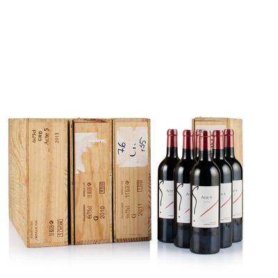 three bottles of red wine in a wooden box next to a stack of boxes