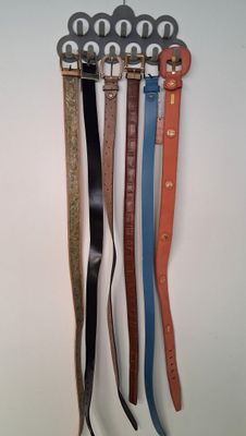 quatre ceintures accrochées à un crochet fixé au mur d'une pièce