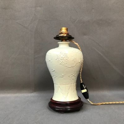une image représentant un vase blanc posé sur un socle en bois, avec une corde