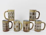 Plusieurs tasses à café sont alignées sur une surface blanche