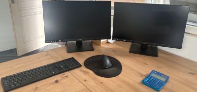 two computer monitors and a keyboard on the table