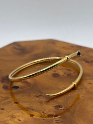 un gros plan sur une paire de boucles d'oreilles créoles en or posées sur une planche en bois