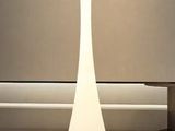 un lampadaire blanc posé sur un tapis dans une pièce