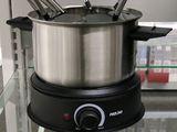 Des casseroles et des poêles sont exposées dans un magasin, accompagnées d'étiquettes de prix