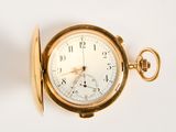 a gold pocket watch on a white surface with a key