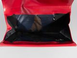 a red bag with a black handle on a white surface