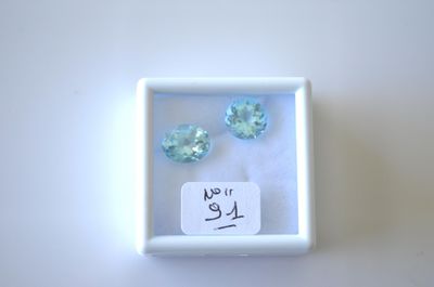 trois pierres précieuses de topaze bleue dans une boîte blanche avec une étiquette de prix