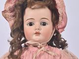 a doll that is wearing a pink dress and a pink hat