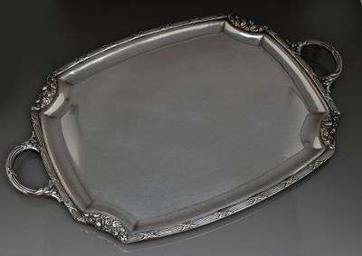 un plateau en argent muni d'une poignée, posé sur une table