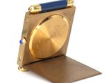 a gold watch with a blue pen on top of it