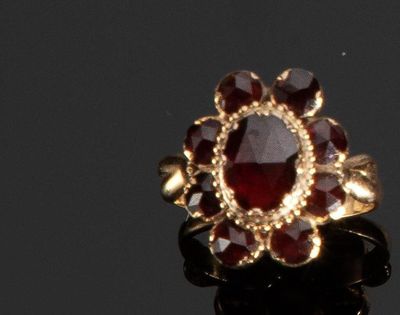 un gros plan d'une bague en or sertie d'une pierre rouge au centre