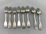 six spoons and six forks are lined up on a table
