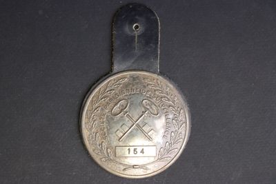 a silver medal with a hammer on it on a black surface