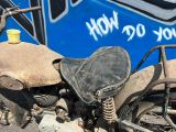 une vieille moto garée devant un bus bleu