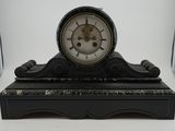 a black and white clock on a stand on a table