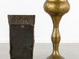 pair of brass candlesticks and a box on a cement floor