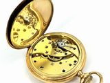a gold pocket watch that is open on a white surface