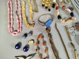 many different necklaces and bracelets laid out on a table