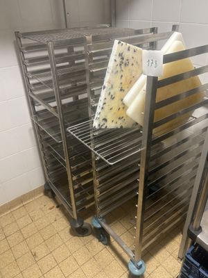 Plusieurs plateaux de fromage sont posés sur une grille métallique dans une cuisine