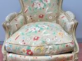 a chair with a floral upholstered seat on a pink floor