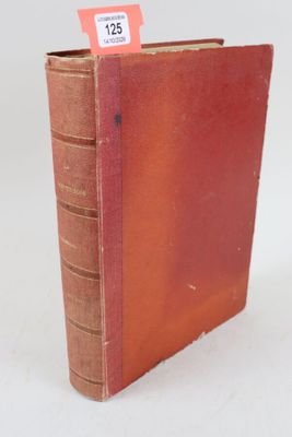 un vieux livre posé sur une table blanche, à côté d'une étiquette rouge