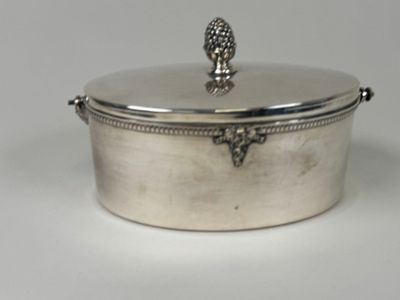 an antique silver plated casserole with a lid on a white surface