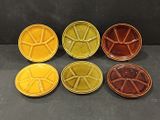 four different colored plates sitting on top of a black surface