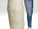 a woman standing next to a tall white vase