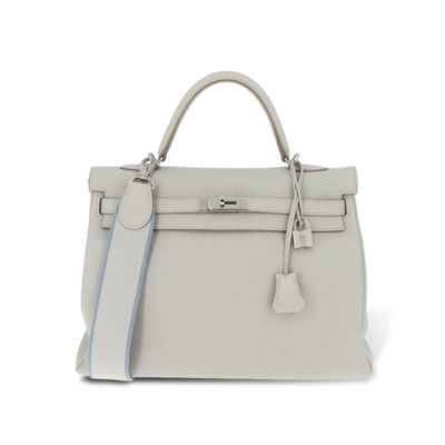 un sac à main en cuir blanc muni d'une bandoulière à rayures bleues