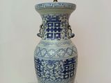 un grand vase bleu et blanc posé sur une table en verre