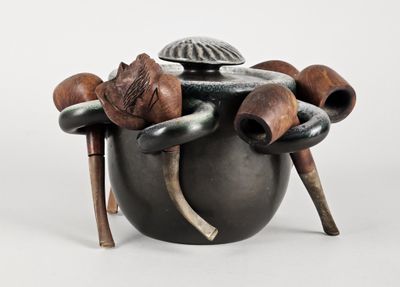 un pot noir muni de poignées en bois et surmonté d'un chapeau