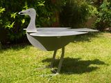 a metal bird that is standing in the grass
