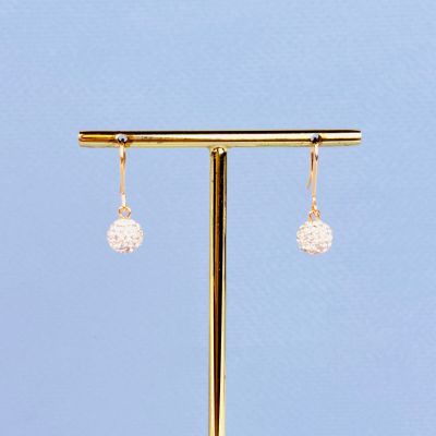 un gros plan sur une paire de boucles d'oreilles posée sur un présentoir en or